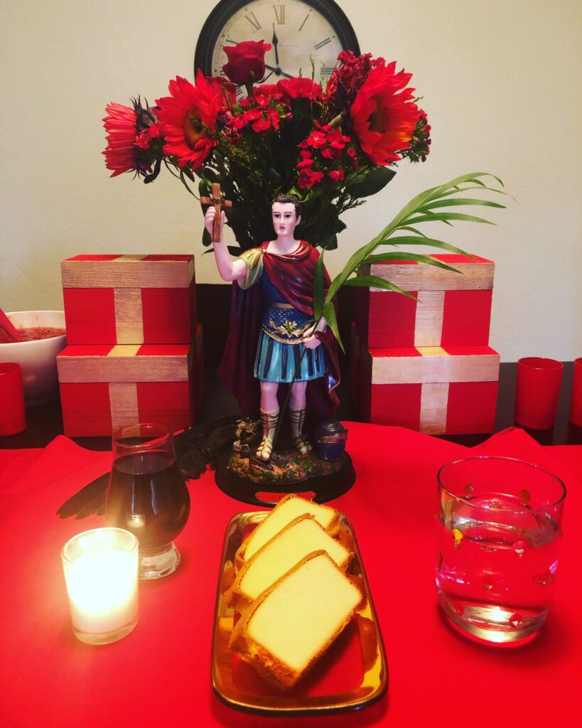 Saint Expedite altar with red carnations, pound cake, and whiskey.